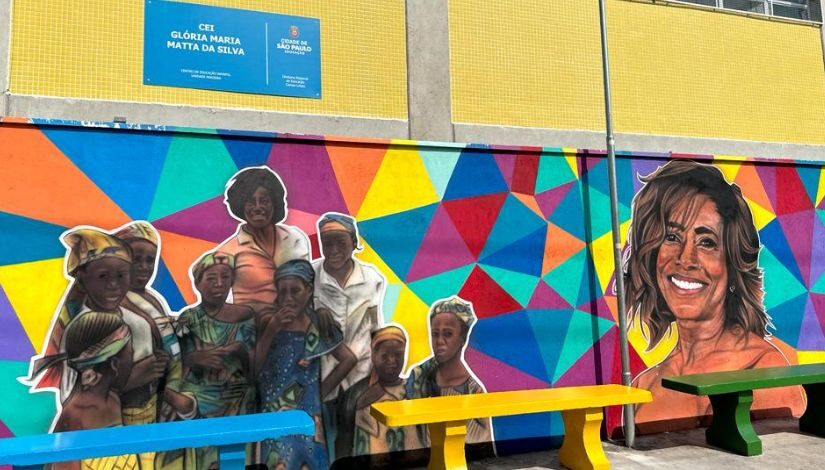 Fachada do Centro de Educação Infantil Glória Maria com grafite colorido com o rosto da jornalista e dela com outras pessoas negras ao seu redor.