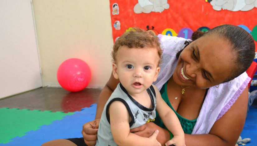 Fotografia de um bebê e uma professora.