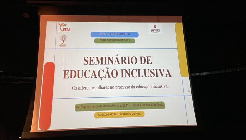 Fotografia mostra um telão onde se lê "Seminário de Educação Inclusiva: Os diferentes olhares no processo da Educação Inclusiva".