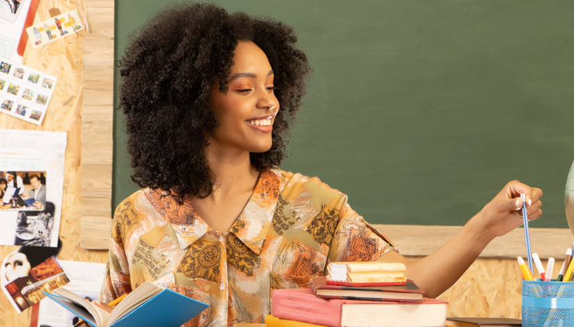 Mulher negra mexendo nos lápis e canetas com livros na mesa