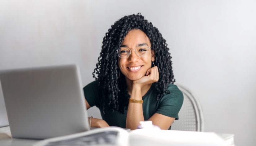 Mulher sorrindo enquanto mexe no computador