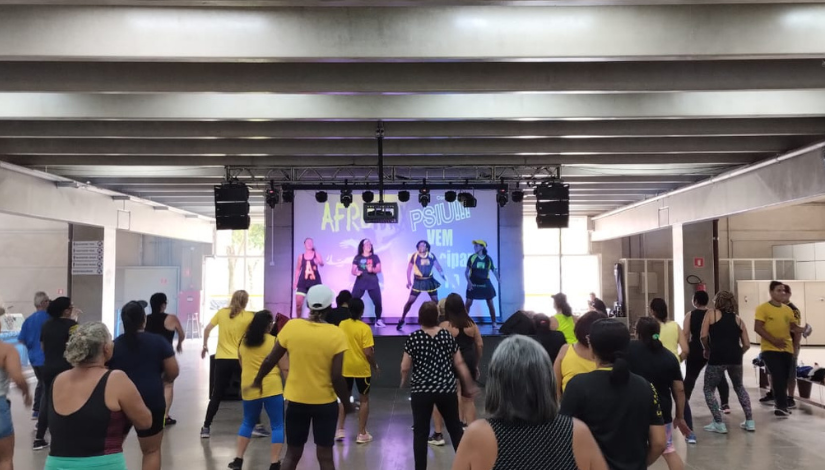 Alunas do CEU Parelheiros participam de aula de Afromix. No palco as professoras conduzem a aula.