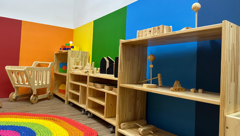 Espaço com brinquedos de madeira e parede colorida
