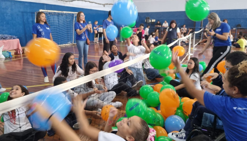 Um grupo de crianças sentadas em uma quadra com uma rede de voleibol baixa