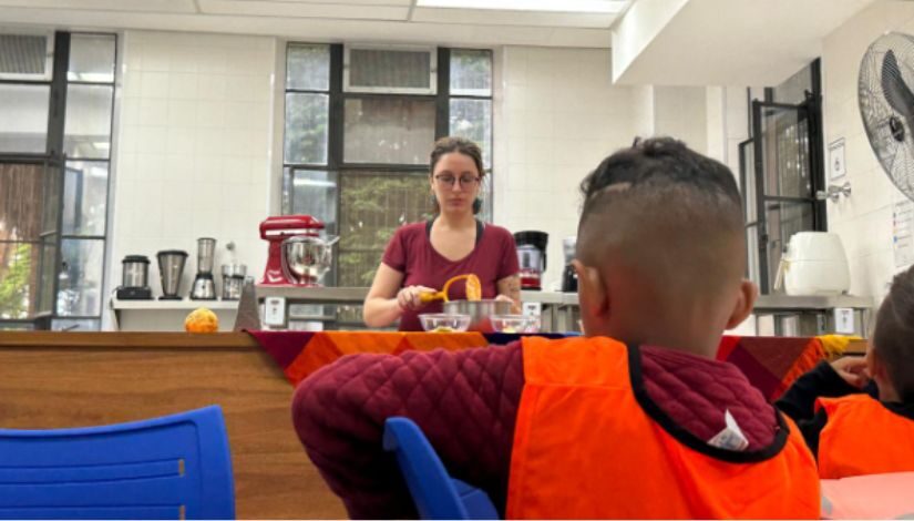 Fotografia mostra mulher cozinhando e criança a olhando.