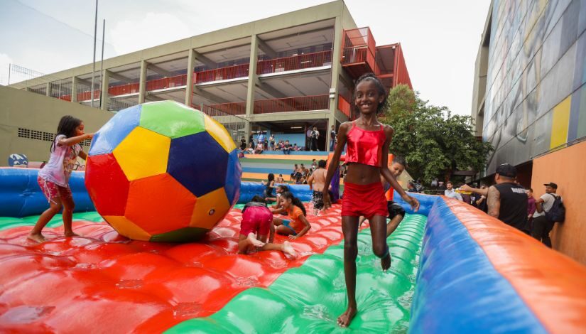 Fotografia mostra crianças em um brinquedo inflável de futebol de sabão.