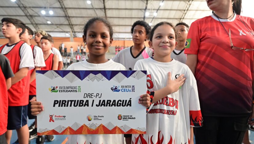 Menina negra com uma camiseta branca segurando uma placa ao lado de uma menina branca e de camiseta branca