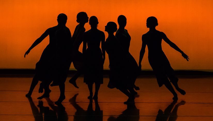 Bailarinos no centro do palco em movimentos de dança.