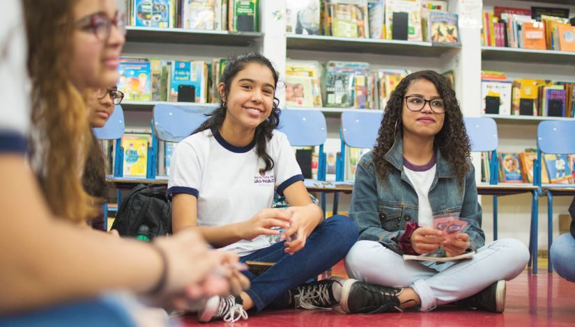 Estudantes em roda de conversa sentadas no chão.