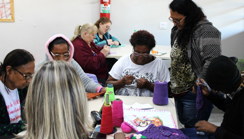 Fotografia mostra grupo de mulheres mostrando trabalhos feitos com crochê no projeto Crochetando Poesia