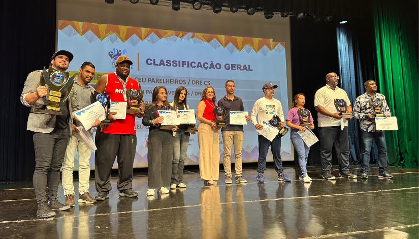 Uma imagem com um grupo de pessoas segurando troféus e sorrindo