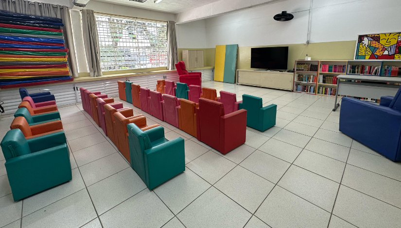 Sala de aula com poltronas coloridas e uma televisão