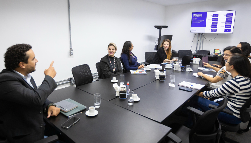 Fotografia mostra grupo de pessoas em uma mesa de reunião