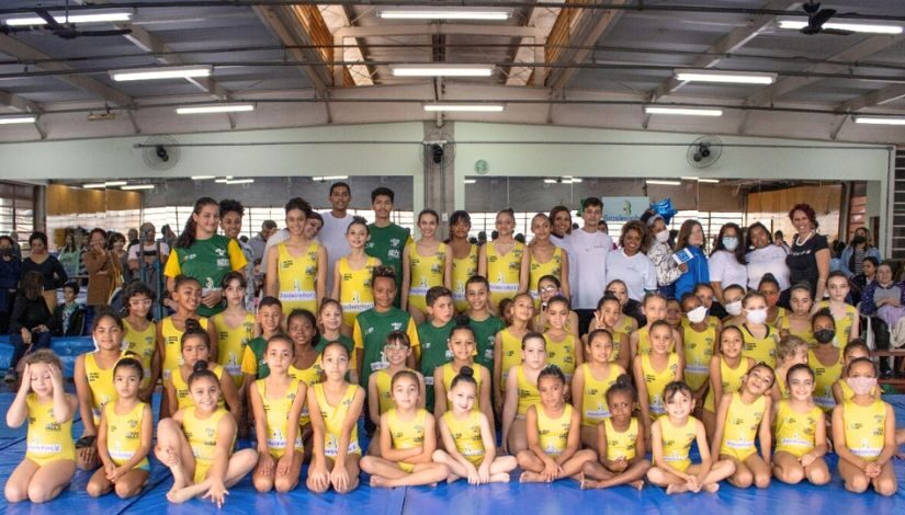 Fotografia mostra diversas crianças participantes do Projeto Brasileirinhos com Daiane dos Santos.
