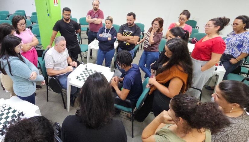 Professor de xadrez ao centro durante formação para educadores na DRE Freguesia/Brasilândia.