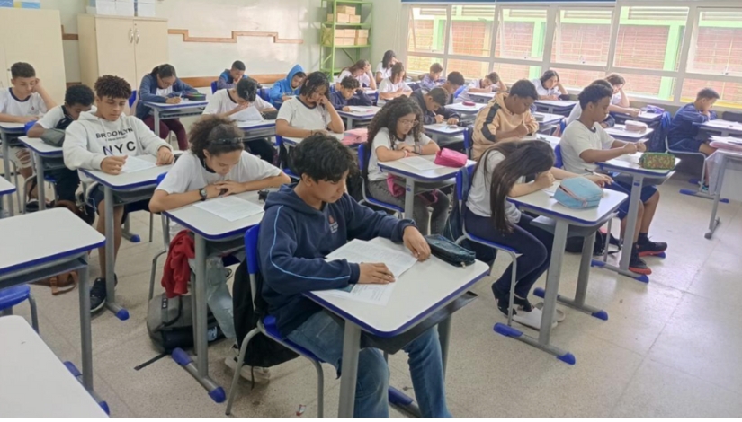 Imagem com uma sala de aula com estudantes concentrados fazendo prova