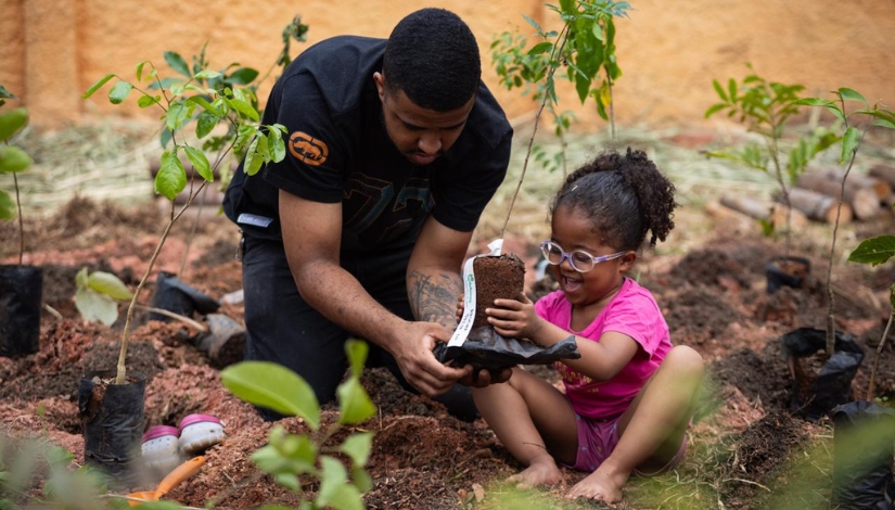 Homem plantando sementes na terra com uma criança de rouba rosa