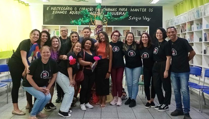 Imagem de várias pessoas de camiseta preta em pé posando para fotografia.