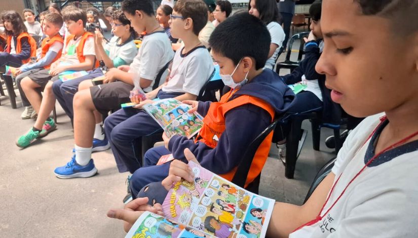 Fotografia de estudantes sentados segurando o gibi da Turma da Mônica - 