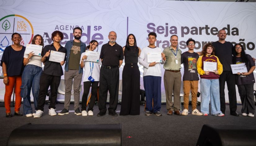 Fotografia mostra várias pessoas em um palco sendo homenageadas na ação 