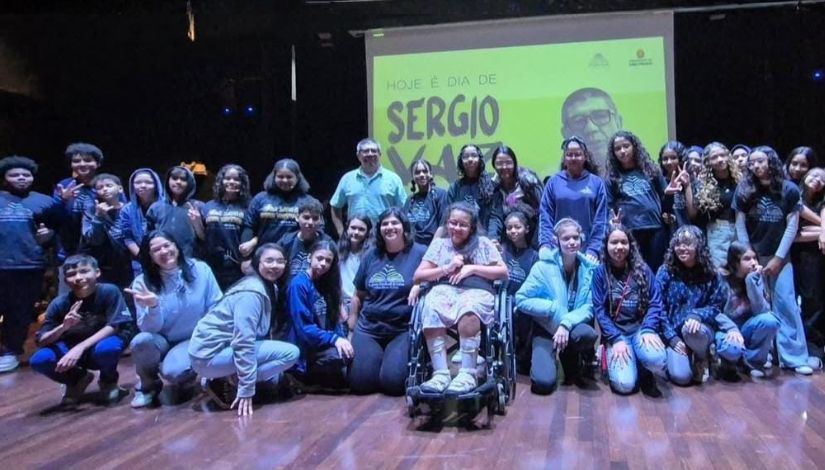 Fotografia de vários estudantes da Academia Estudantil de Letras com o escritor Sérgio Vaz no palco do CEU Vila Rubi.