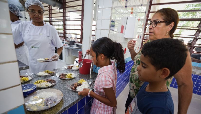 crianças recebendo prato de comida de cozinheira