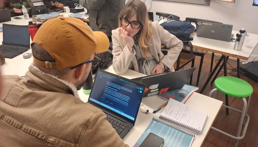 Dois adultos reunidos com notebooks sobre a mesa.