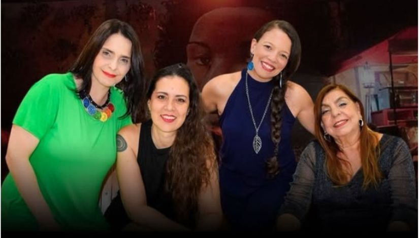 Quatro mulheres sorrindo, pousando para foto de perfil frontal.