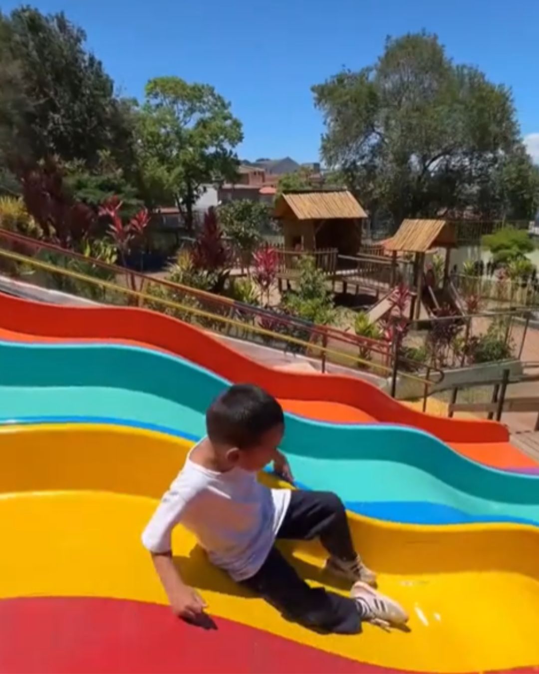 Criança descendo em um tobogã colorido nas cores amarela, verde, vermelha.