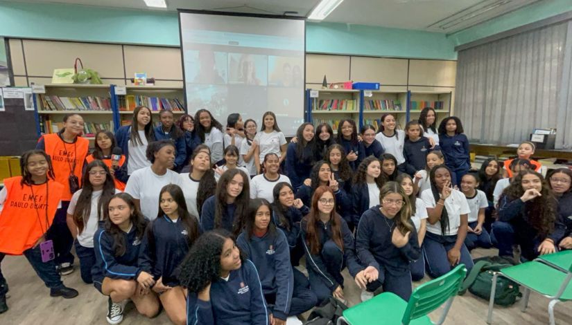 Fotografia de um grupo de meninas em frente ao telão do bate-papo virtual.