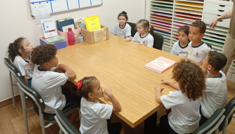 Fotografia de crianças sentadas ao redor da mesa durante reunião do Conselho Mirim.