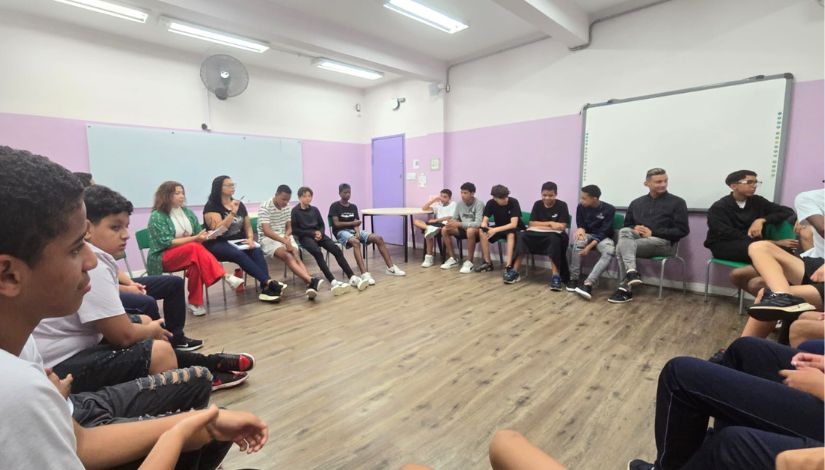 Fotografia de uma roda de conversa de meninos com uma escritora. 