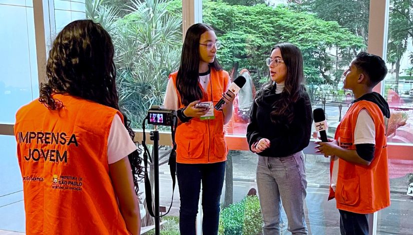 Estudantes com colete laranja escrito 