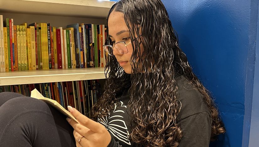 Fotografia de uma menina sentada lendo.