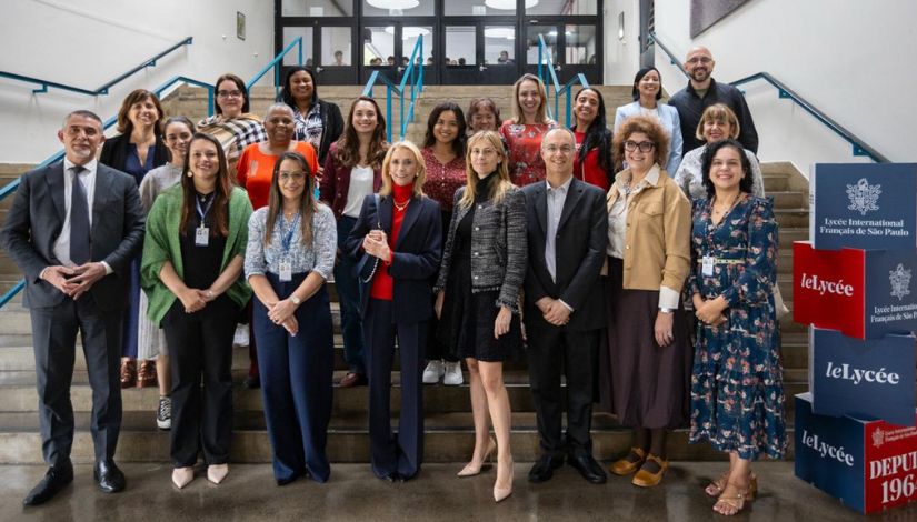Fotografia com vários adultos em pé em frente a escada posando para câmera.