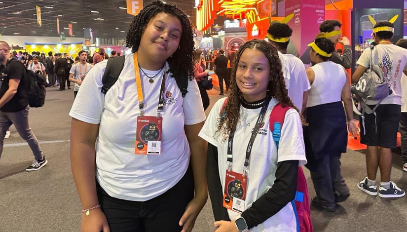 Duas estudantes com uniformes da prefeitura sorriem para a foto