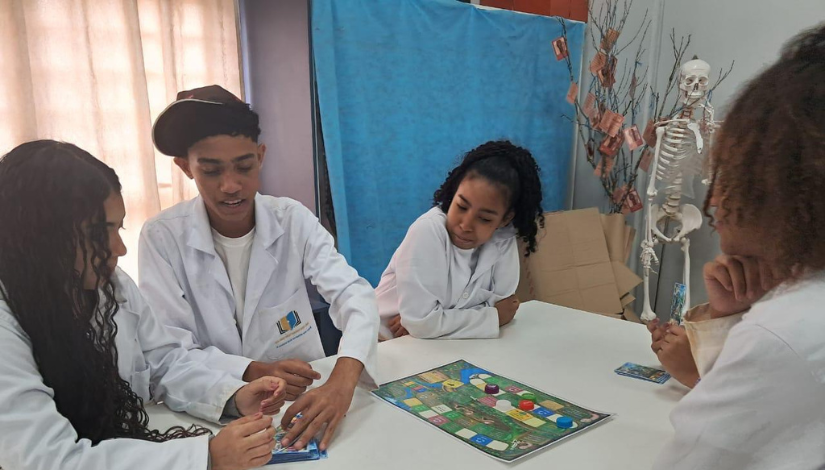 estudantes vestindo jaleco jogando um jogo de tabuleiro