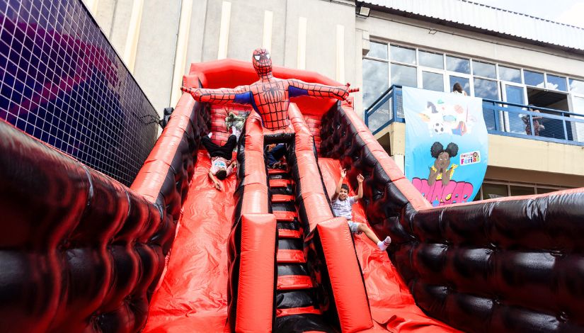Fotografia de um tobogã inflável do Homem Aranha com crianças escorregando.