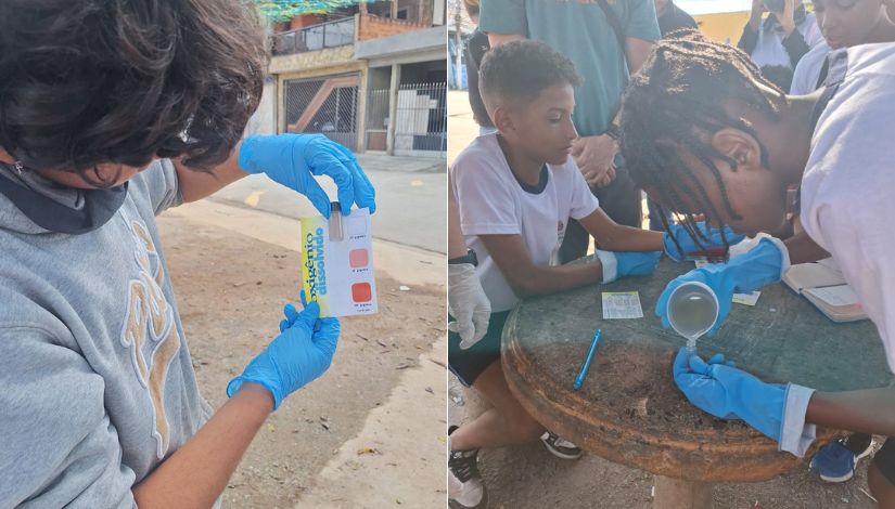 Estudantes realizam análise da qualidade da água em atividade de campo, utilizando luvas, materiais de medição e observação de amostras durante uma ação de educação ambiental.