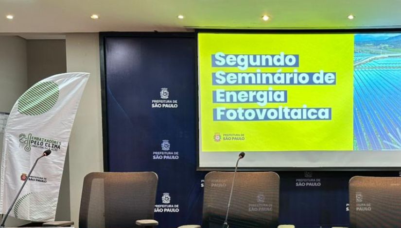 Fotografia com imagem projetada em um telão e o texto 