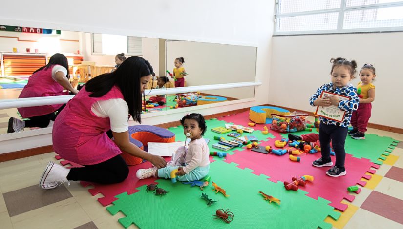 Fotografia de uma professora com os bebês na sala.