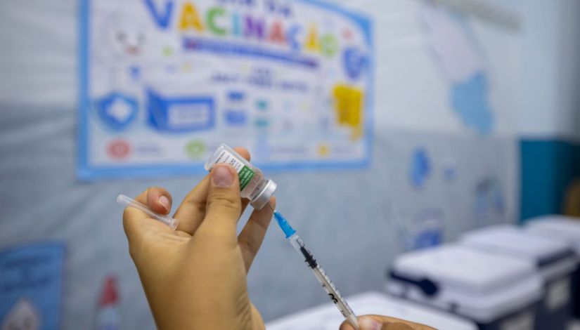 Fotografia de mãos segurando um frasco de vacina e um injeção .