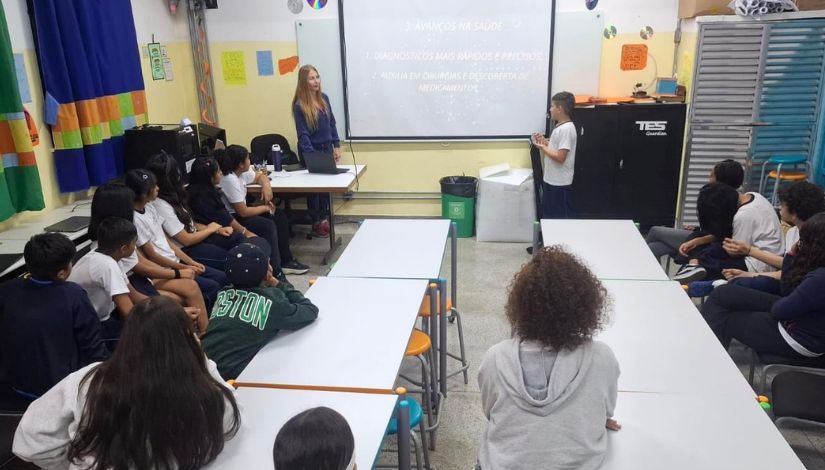 Fotografia de estudantes e professora em sala de aula.