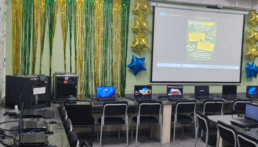 Fotografia de uma sala de aula decorada para Copa do Mundo com as cores verde, amarela, azul e uma projeção no telão com o texto 