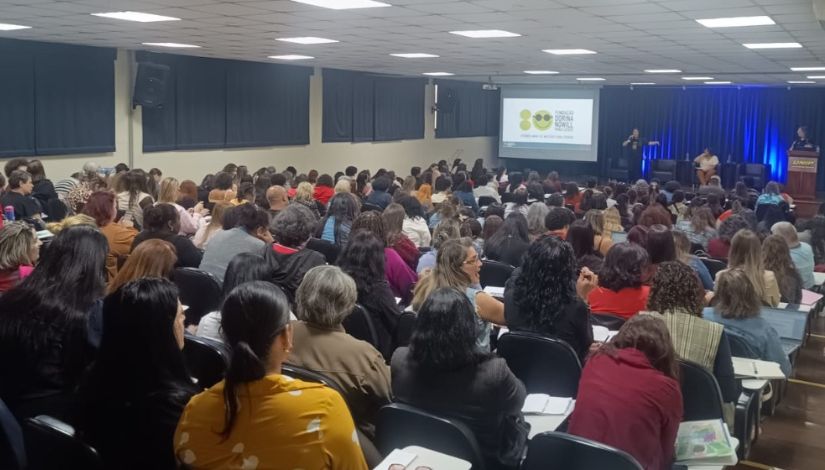 Fotografia de um auditório repleto de pessoas sentadas em momento de palestra.