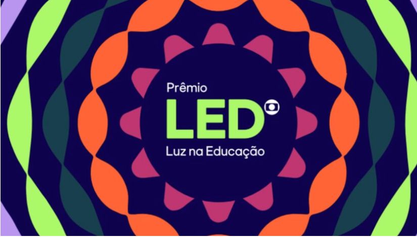 magem horizontal com fundo azul-escuro e composição gráfica circular formada por formas geométricas em verde-claro, azul-petróleo, laranja, rosa e lilás. No centro, sobre um círculo azul-escuro, aparece o texto “Prêmio LED – Luz na Educação”, com “LED” em letras grandes na cor verde-claro e o símbolo do prêmio ao lado.