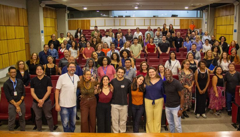 Fotografia de vária pessoas em pé em um auditórrio.