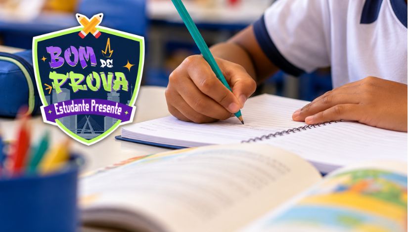 Imagem de uma sala de aula, com destaque para as mãos de um estudante escrevendo com lápis em um caderno aberto sobre uma mesa. Ao fundo, aparecem outros materiais escolares e elementos da sala desfocados. À esquerda, está o logotipo do programa “Bom de Prova – Estudante Presente”, em formato de escudo, com cores azul, verde, roxo e amarelo.