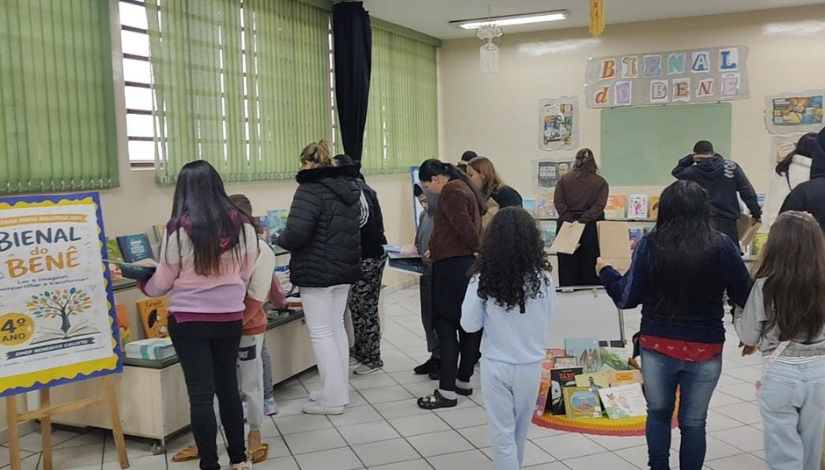 Grupo de pessoas em uma sala de leitura de uma escola olhando livros espalhados